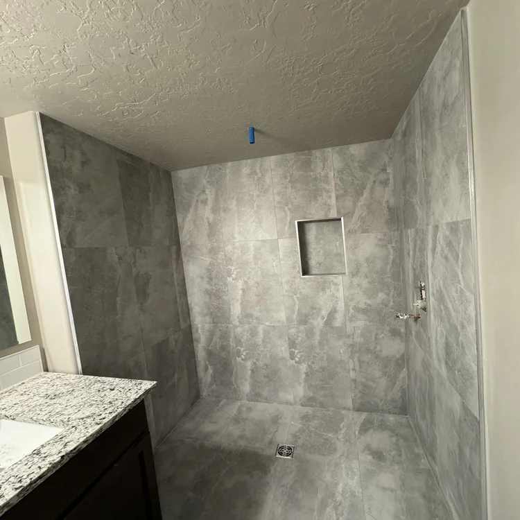 Walk-in shower with large-format marble-look tile walls and a tiled shower floor, mid-remodel
