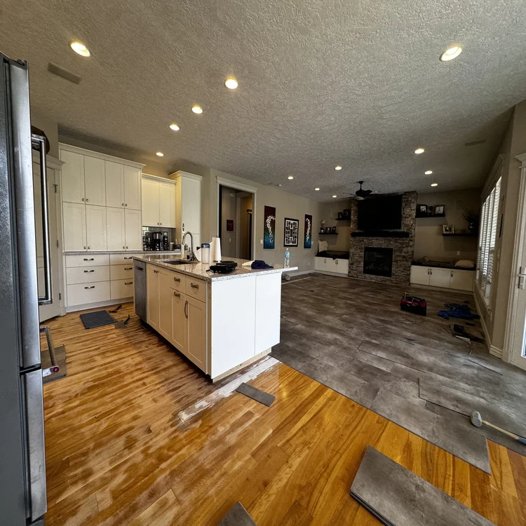 Wood-look luxury vinyl plank flooring being installed in an open-concept kitchen and living room